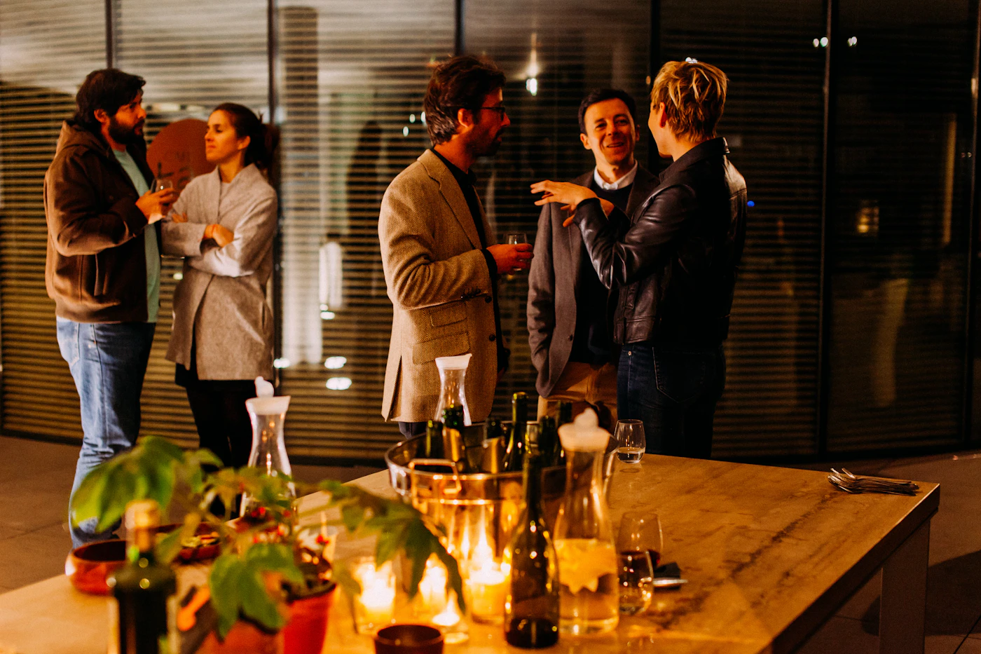Five people chatting in small groups at an evening gathering